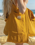 Turmeric Hemp Market Bag carried over a shoulder at the beach, with a blanket secured underneath